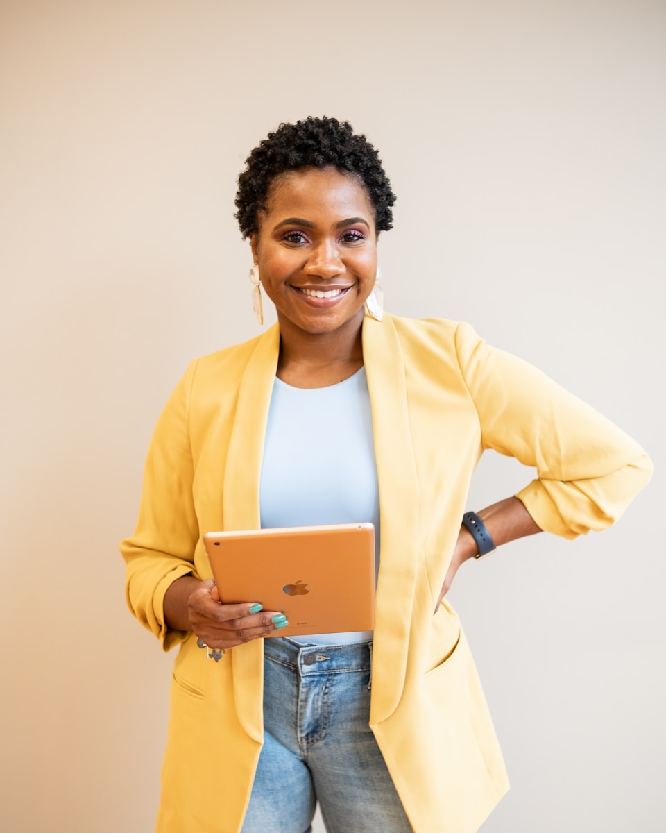 woman in yellow blazer and blue denim jeans smiling